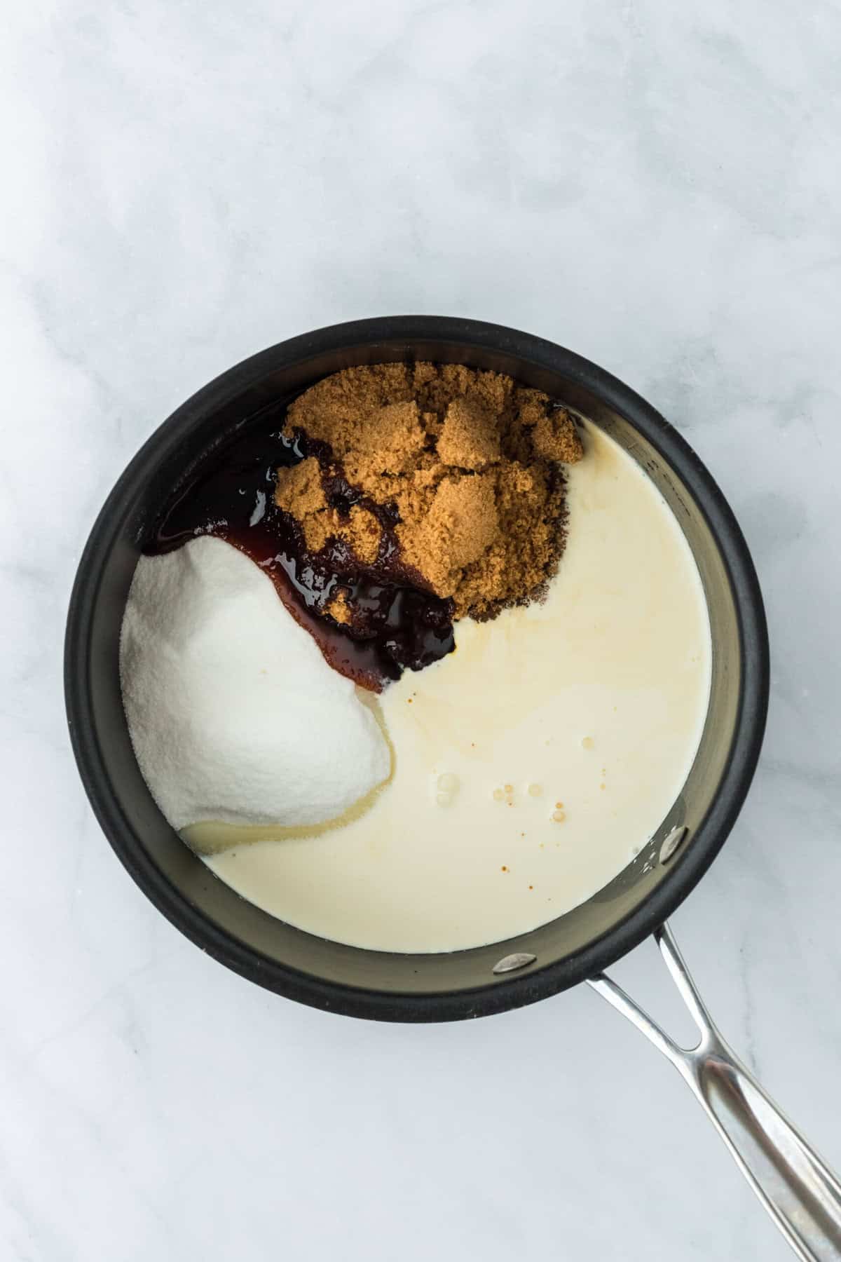 Brown sugar, white sugar, molasses and cream added to a pot on a white background