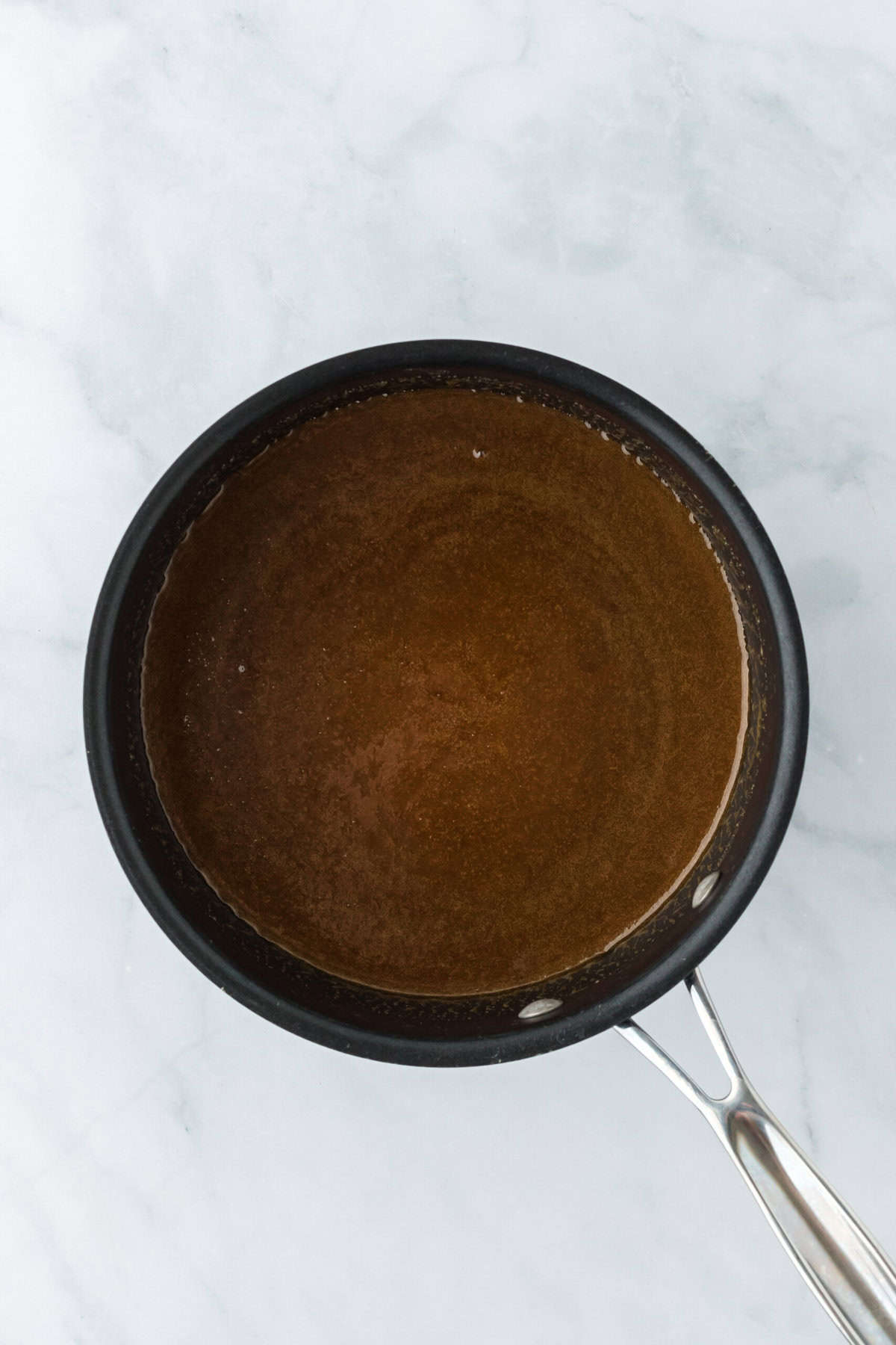 Pecan praline mixture stirred together in a large pot on white background