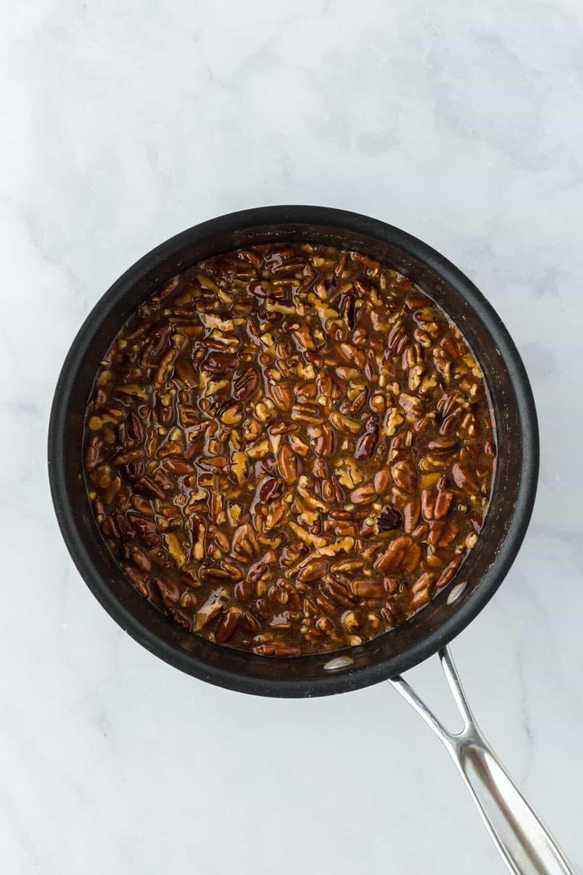 Praline candy mixture stirred together in large pot on white background