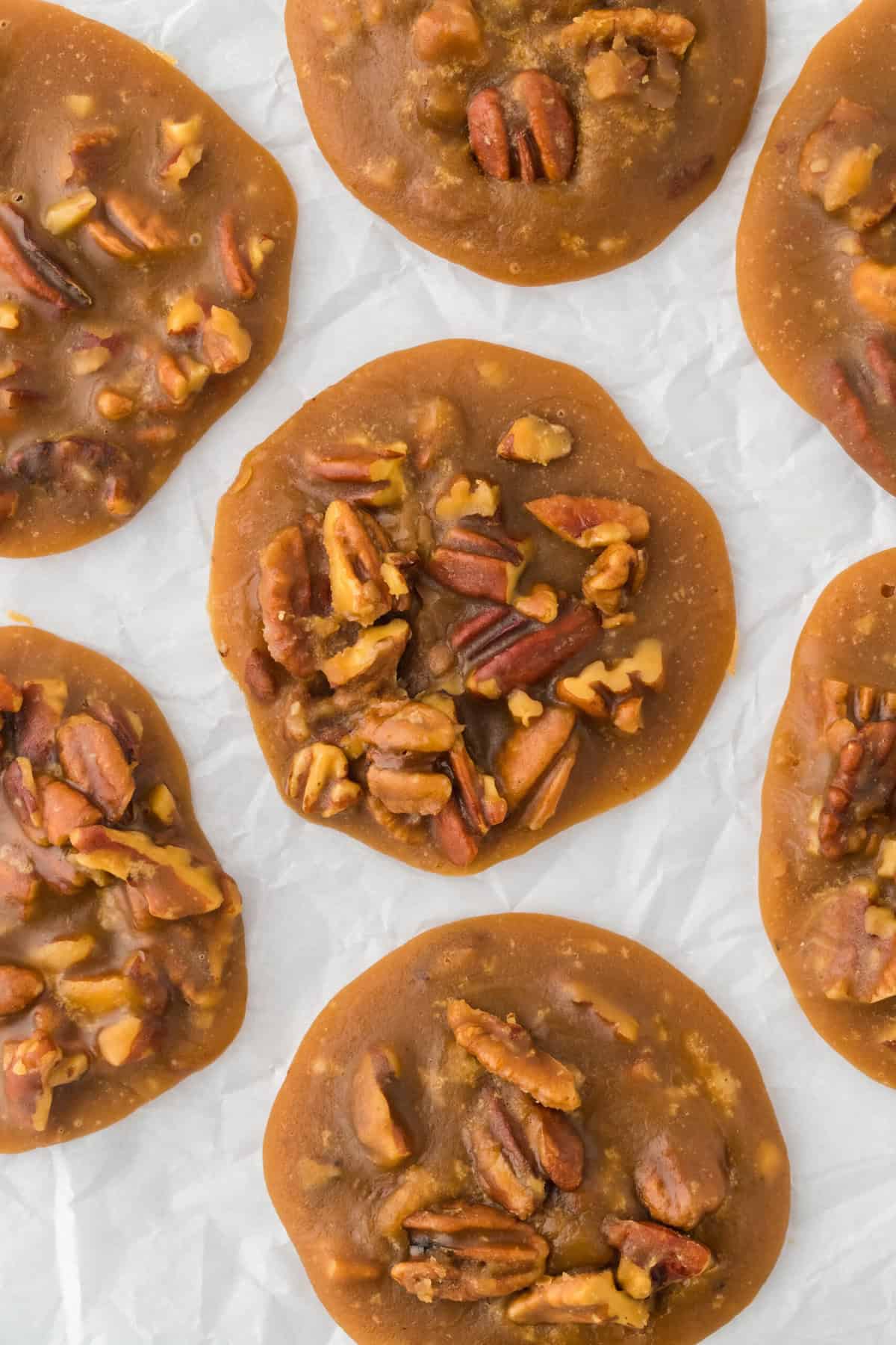 Homemade praline pecans scattered on parchment paper overhead.