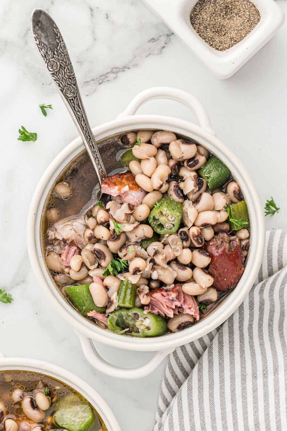 A bowl of black eyed peas on the table with a spoon in it.