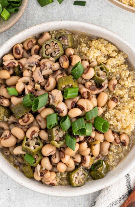 Two bowls of hoppin john recipe served on quinoa in white bowls ready to enjoy