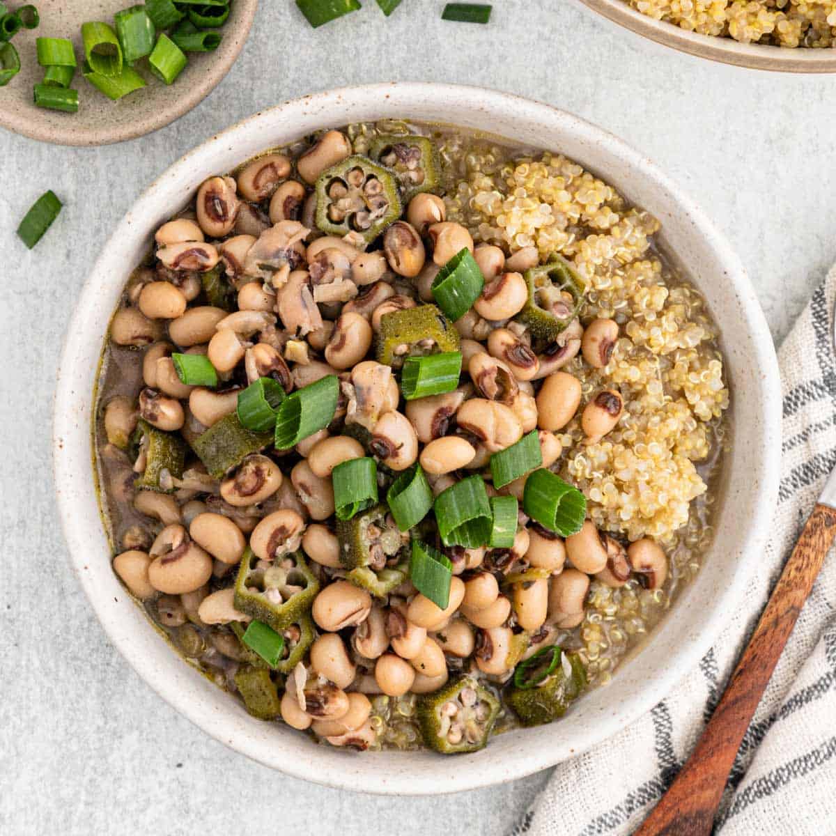 Two bowls of hoppin john recipe served on quinoa in white bowls ready to enjoy for New Year's Day