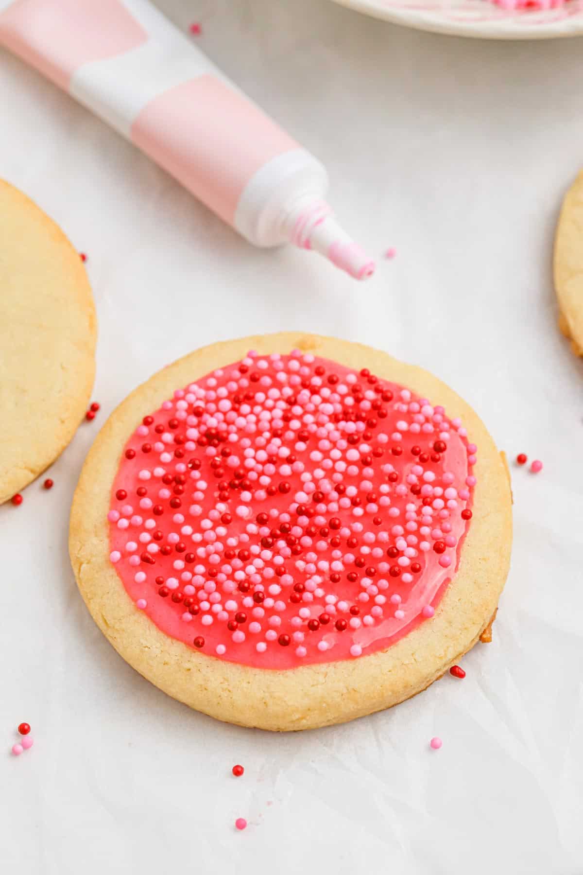 A single sugar cookie with pink frosting and sprinkles.