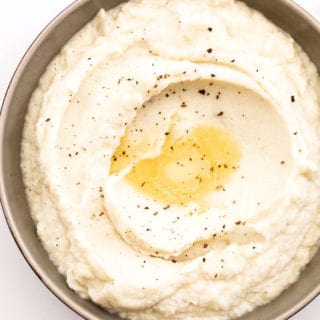 An overhead of keto grits with melted butter and pepper ready to serve