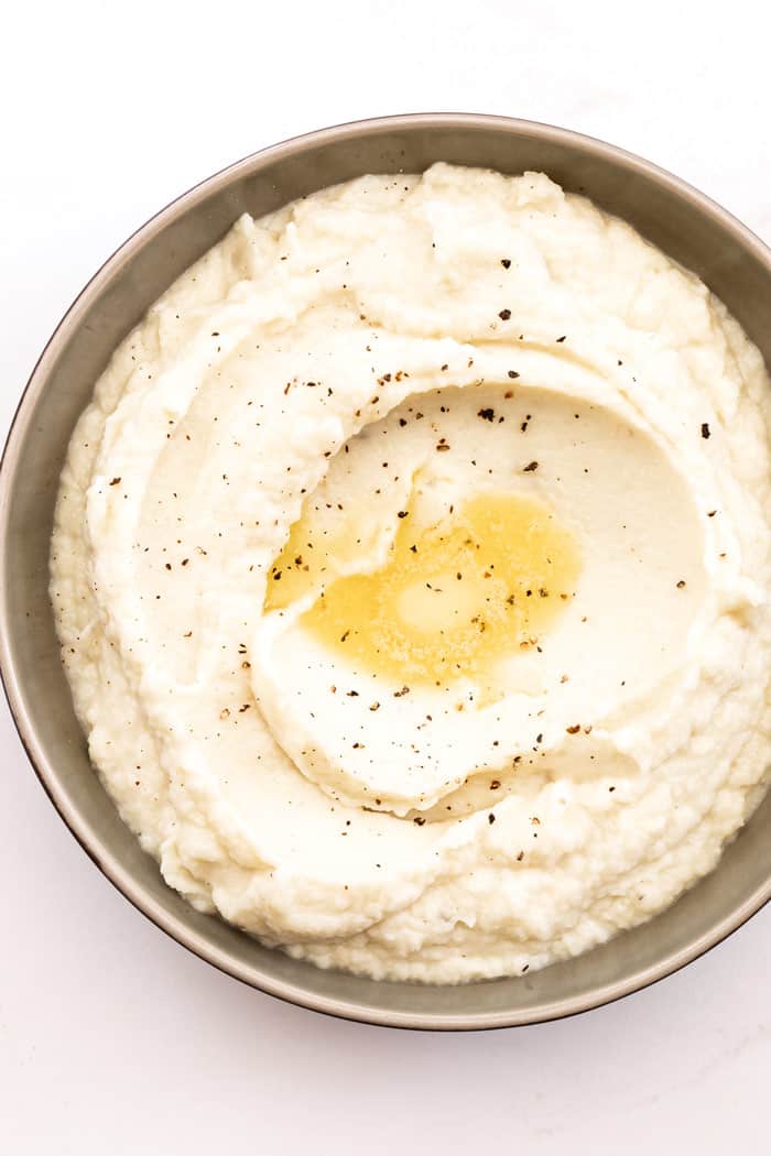 An overhead of keto grits with melted butter and pepper ready to serve