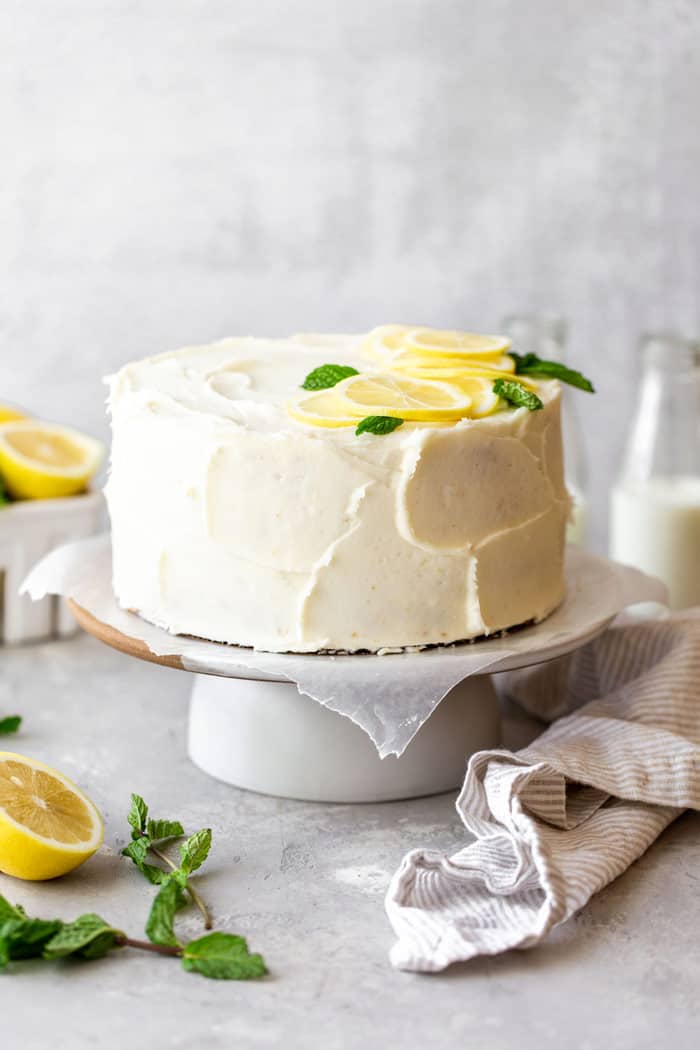 A lemon cream cheese frosting covered layer cake with lemon and mint garnishes