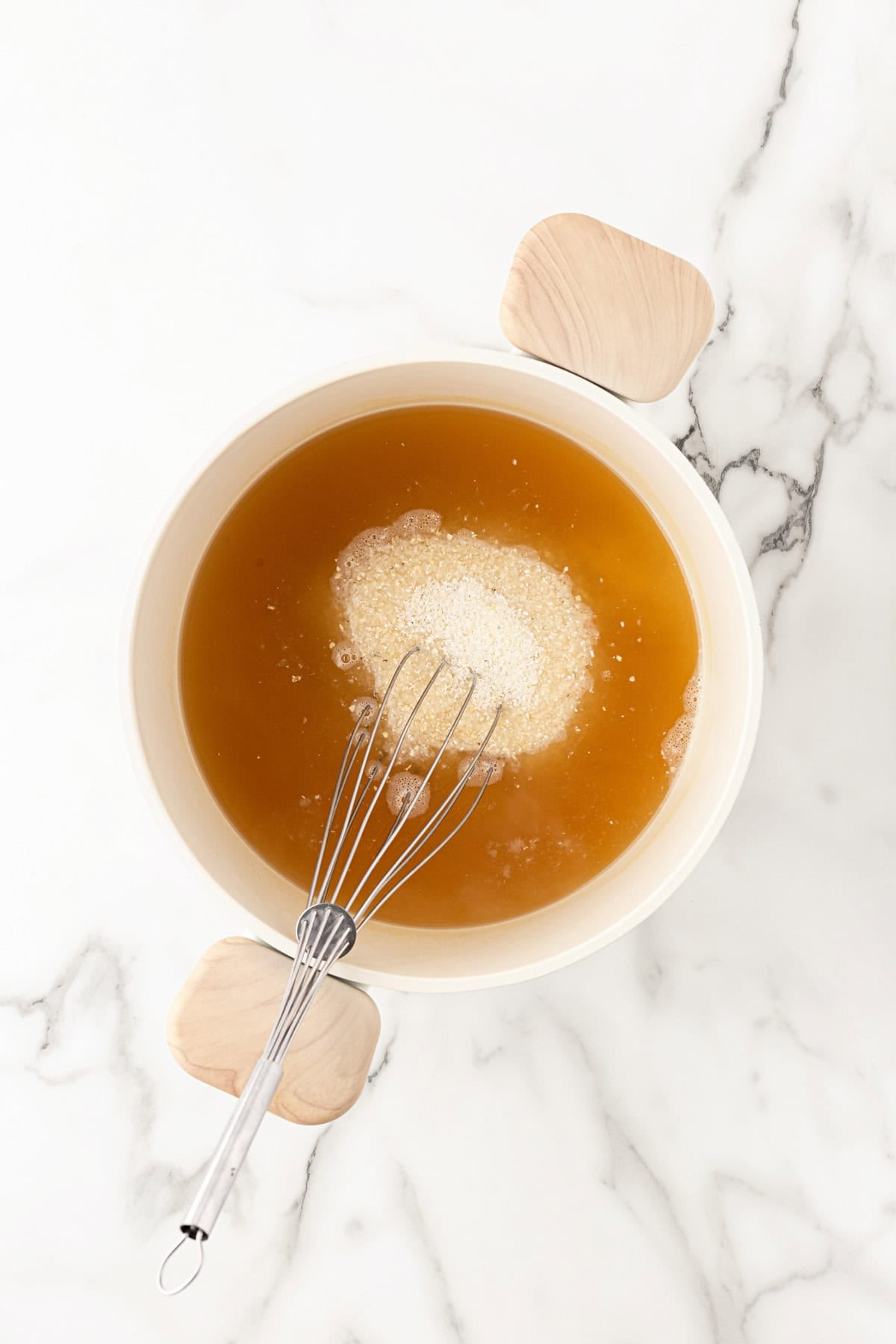 Grits being whisked into broth in a saucepan