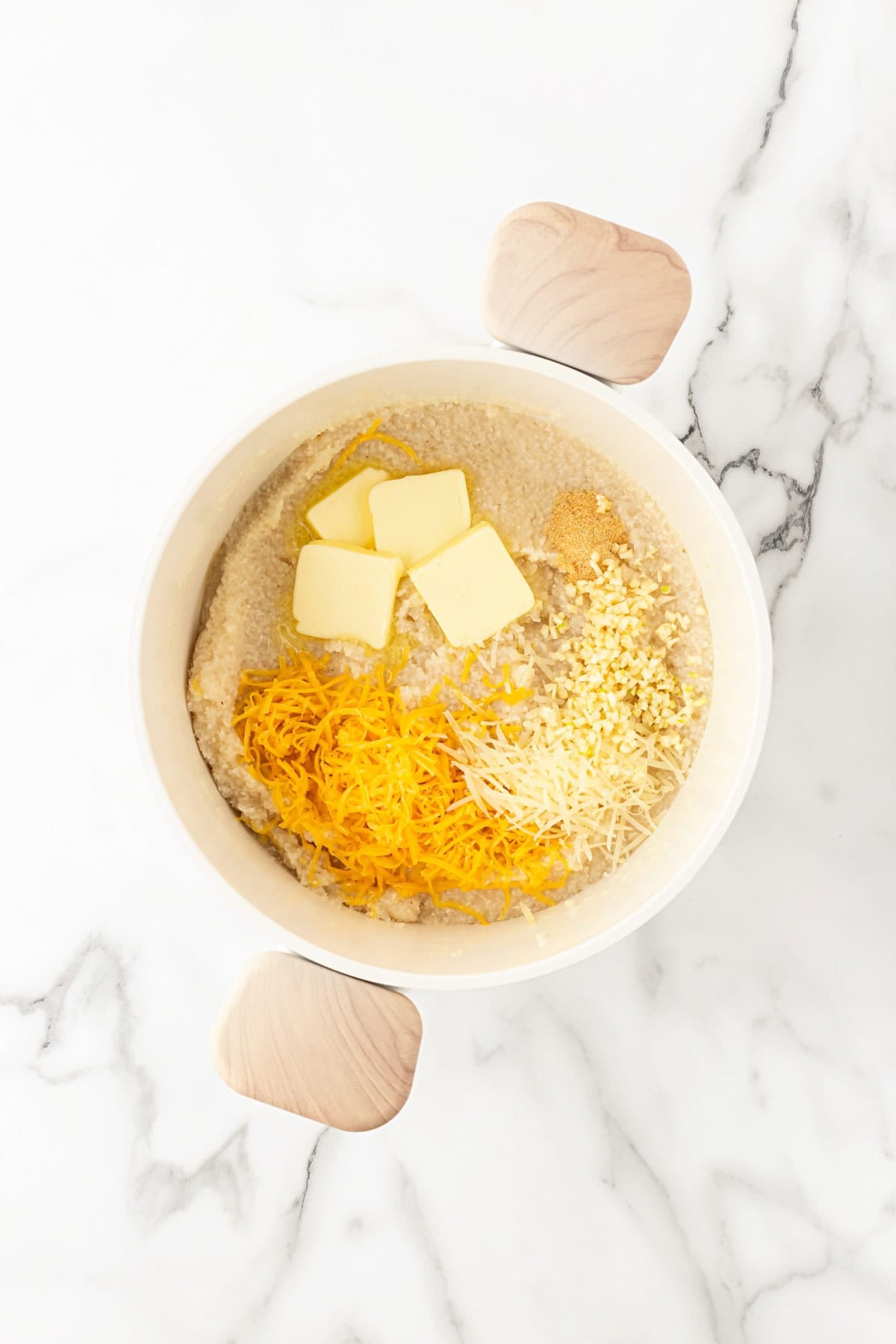 Cooked grits topped with butter, garlic, seasonings, cheddar, and Parmesan