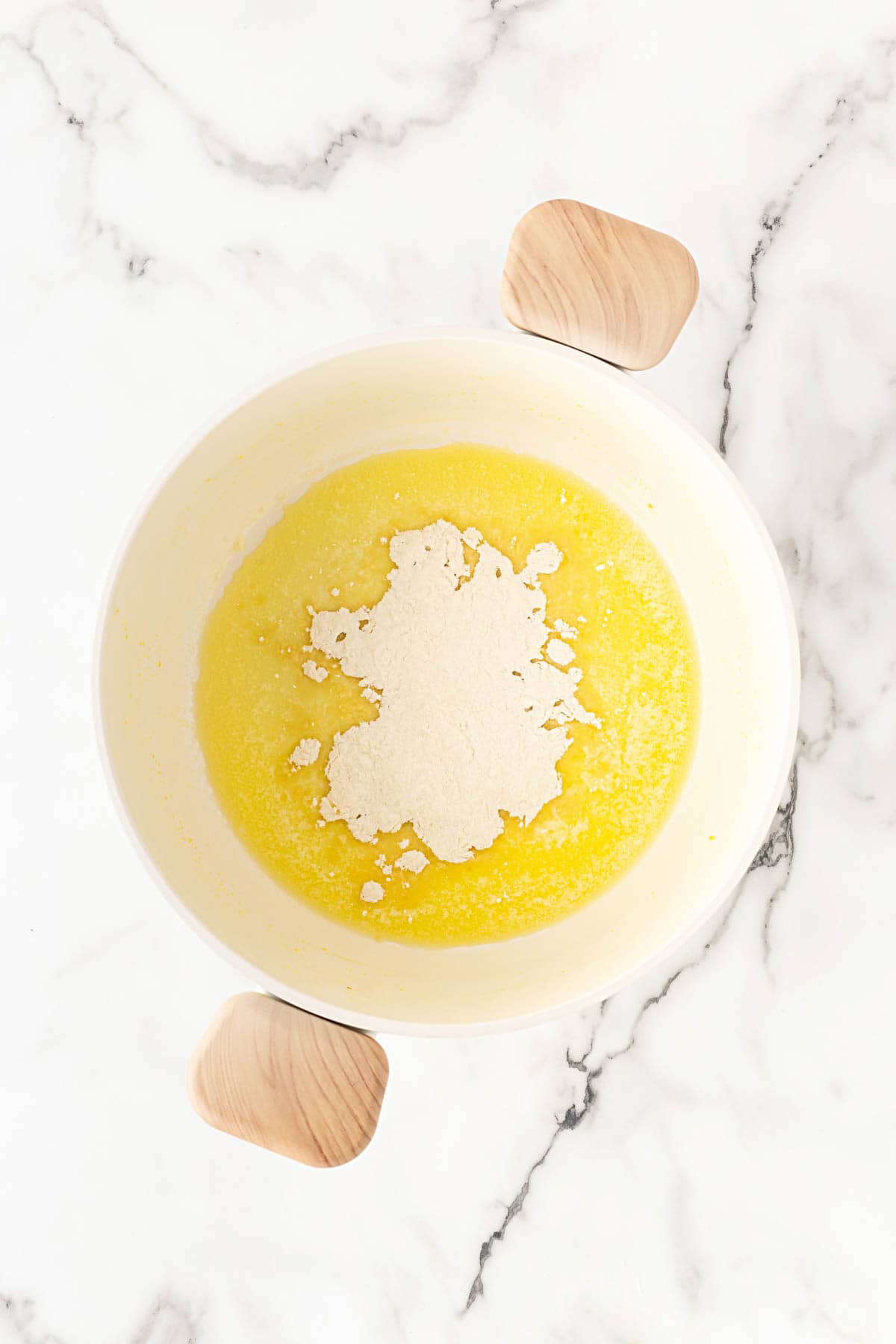 Flour added to melted butter in a pot to form a roux