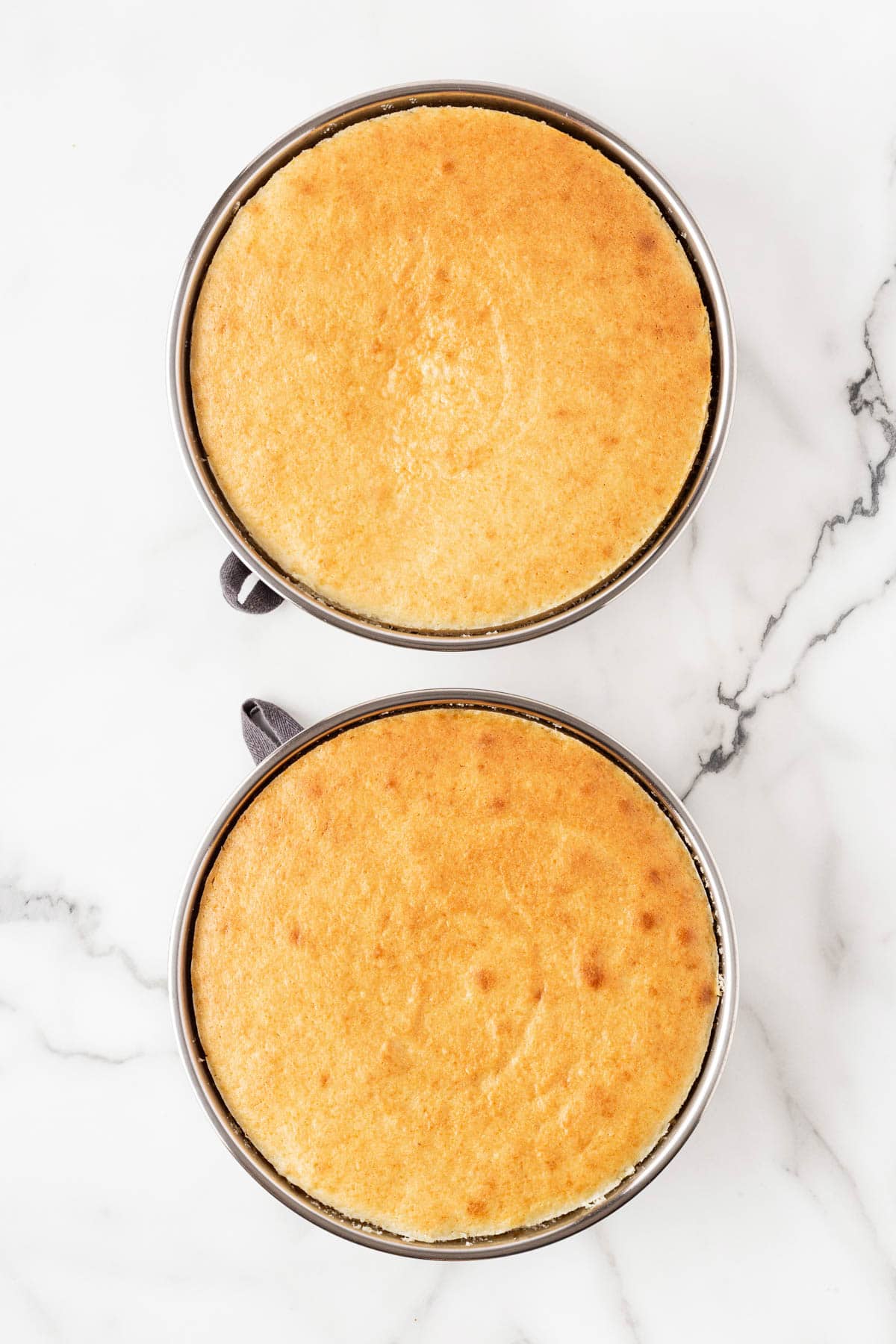 Two freshly baked lemon cake layers still in their pans