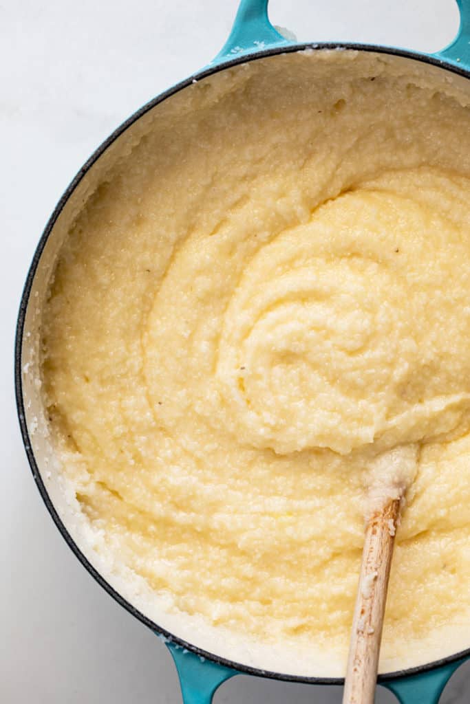 Creamy cheese grits being stirred on stovetop