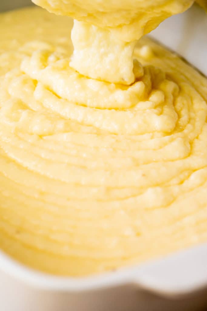 Southern grits made with cheese and garlic being poured into casserole dish to bake