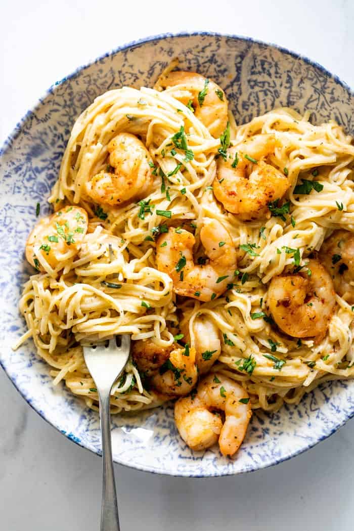 A large bowl of shrimp scampi with fork twirling pasta around