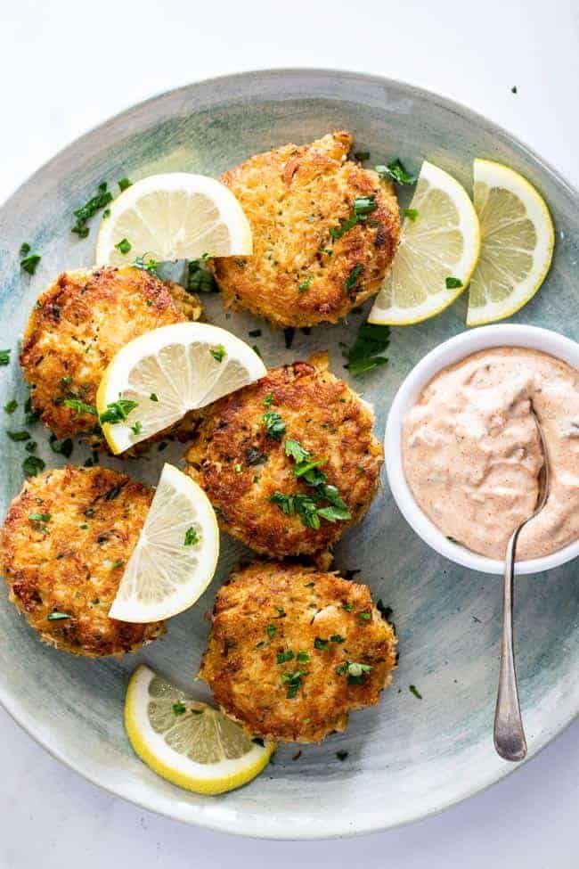 Gorgeous crab cakes scattered with lemon wedges and remoulade sauce ready to serve