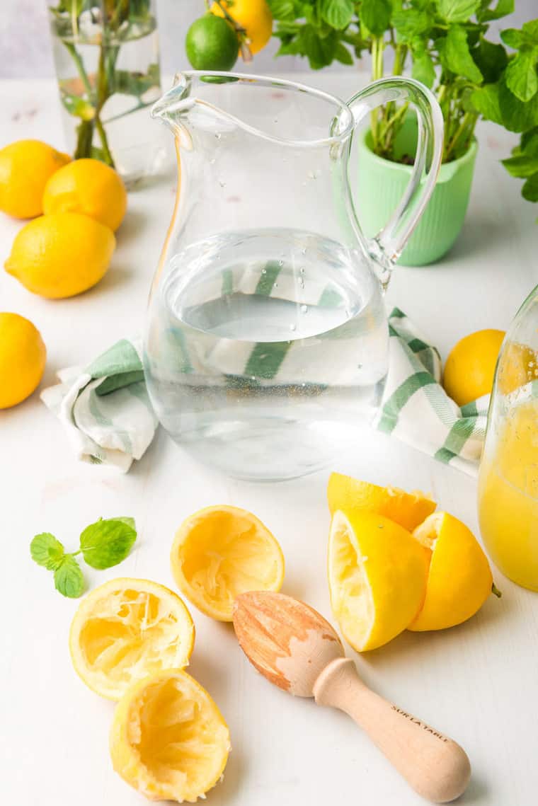 Pitcher filled with water with squeezed lemons surrounding