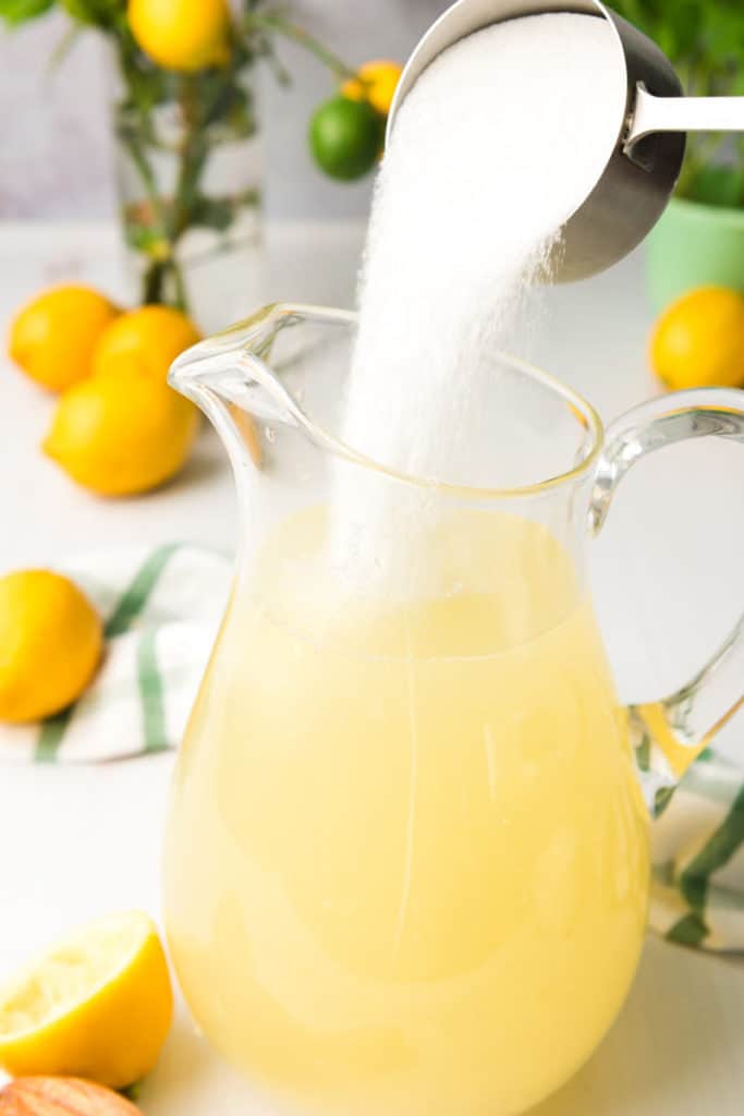 Sugar being poured into lemon water to make southern lemonade