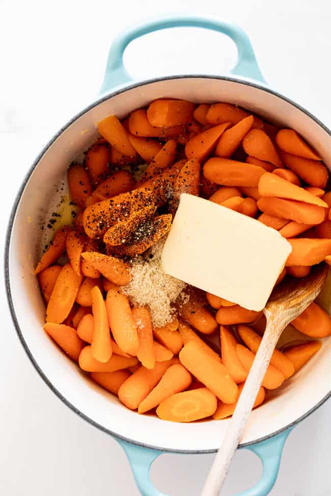 Butter, sugar and other ingredients in pot with carrots ready to make glazed