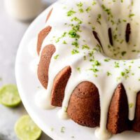 A close up of full key lime pound cake with cream cheese glaze and lime zest garnish ready to serve on cake platter