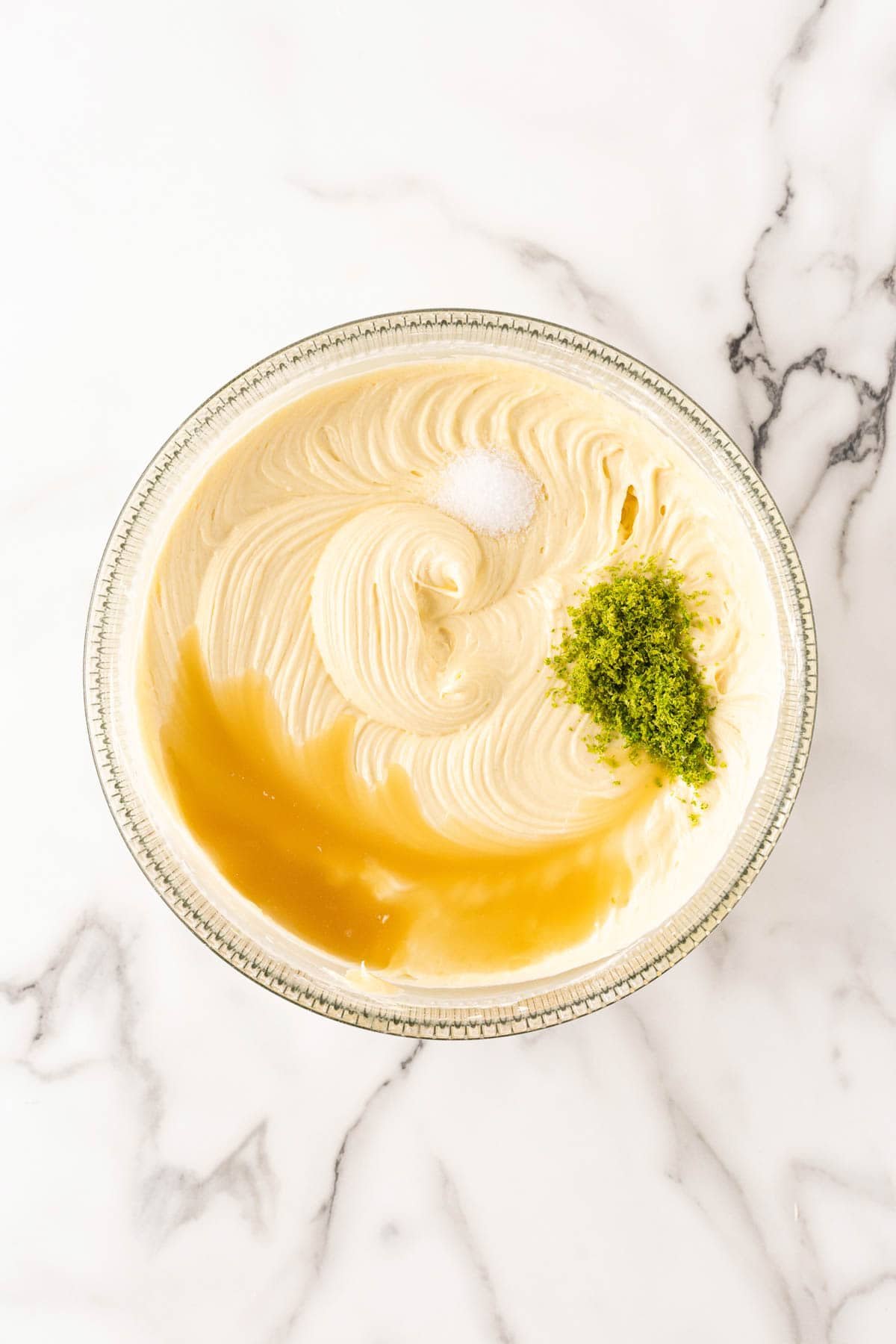 Cake batter in a bowl with salt, lime zest, and lime juice added before mixing