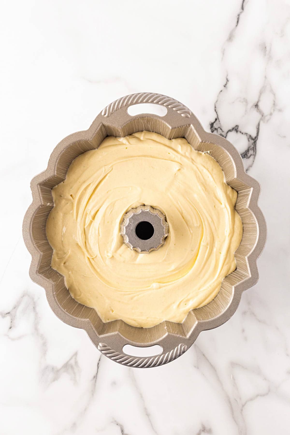 Smooth key lime cake batter spread evenly inside a greased Bundt pan