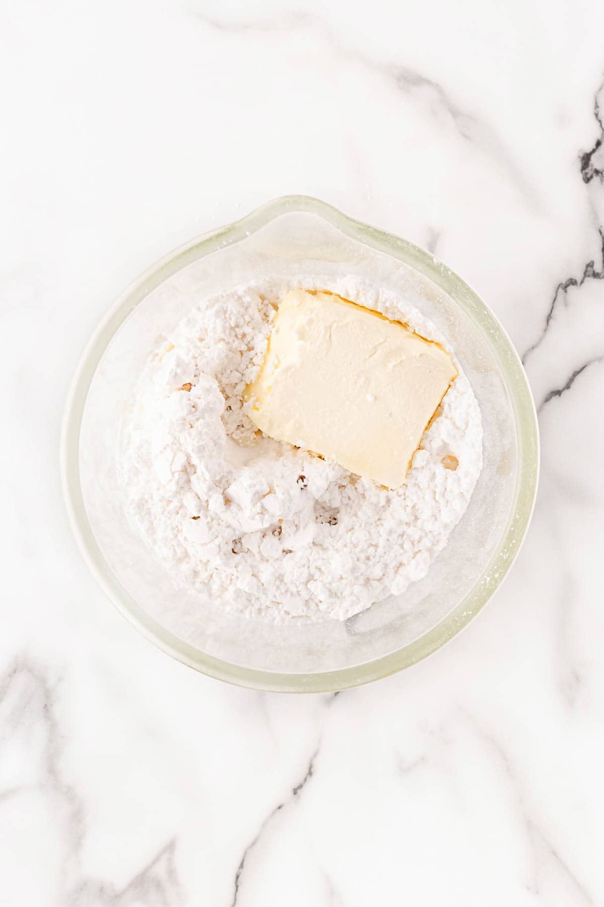 Powdered sugar with softened butter in a bowl, ready to be mixed into glaze