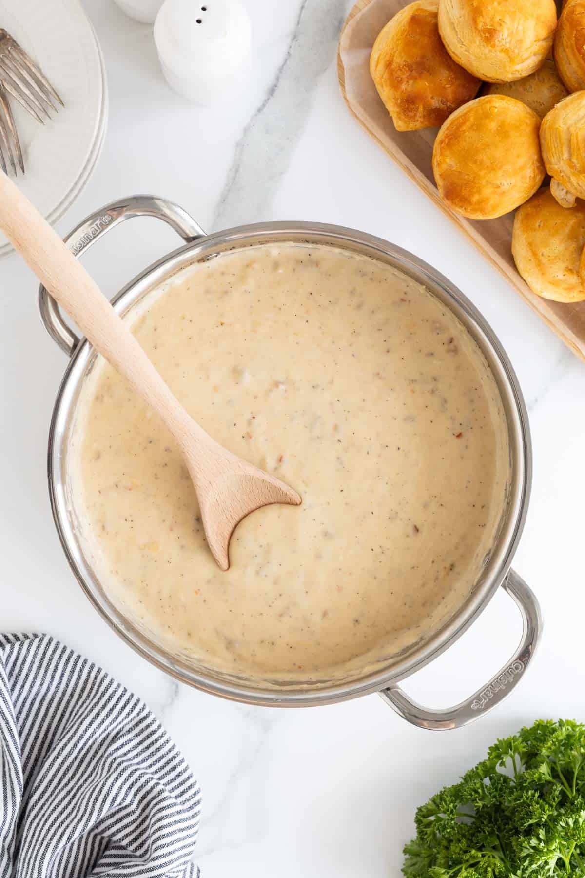 Finished sawmill gravy in a pot with a wooden spoon, ready to serve