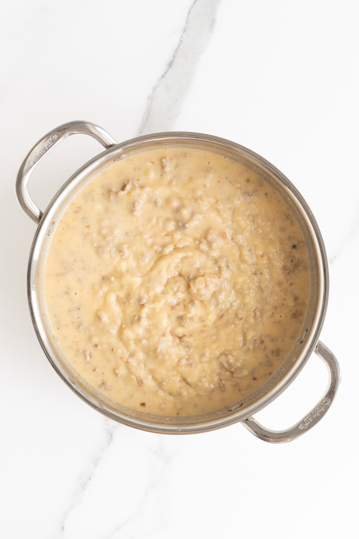 Thickened sausage gravy starting to come together in the pan after adding the wet ingredients
