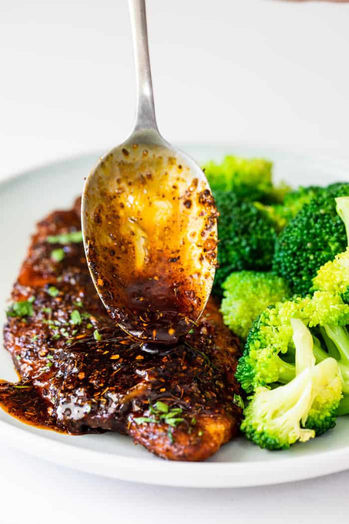 Honey glaze being poured over blackened fish served with broccoli