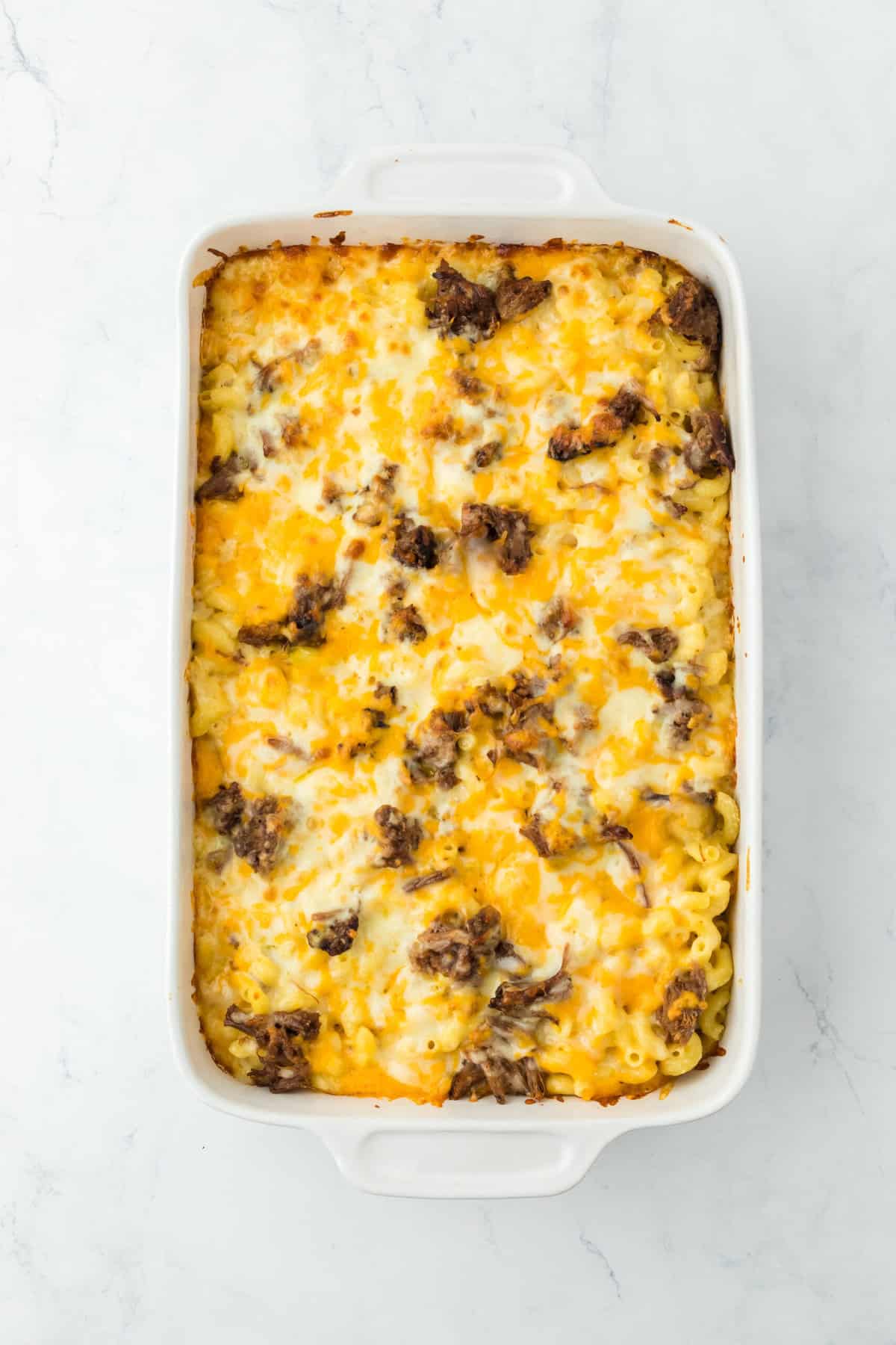 Completed brisket macaroni and cheese right out of the oven on white countertop.