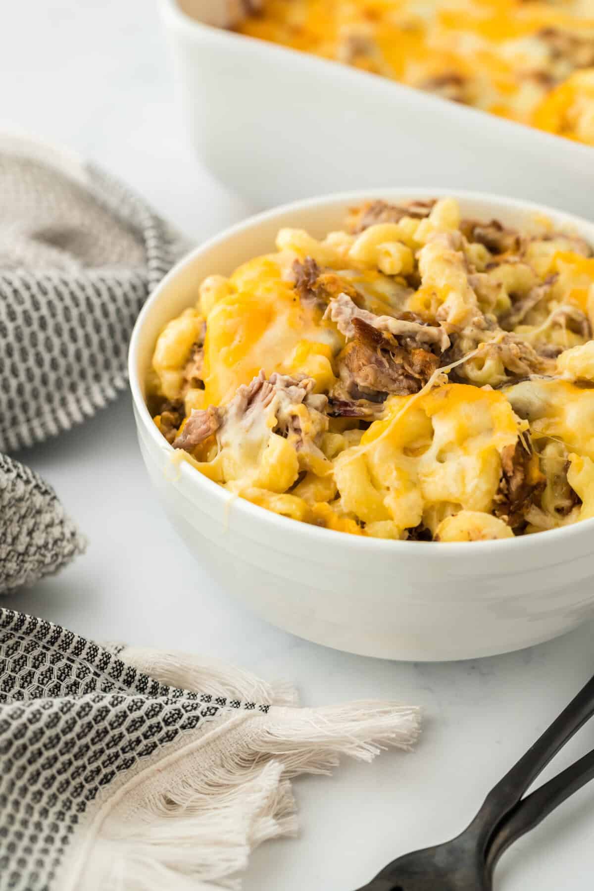 A large white bowl of the best brisket mac and cheese recipe on a white countertop 