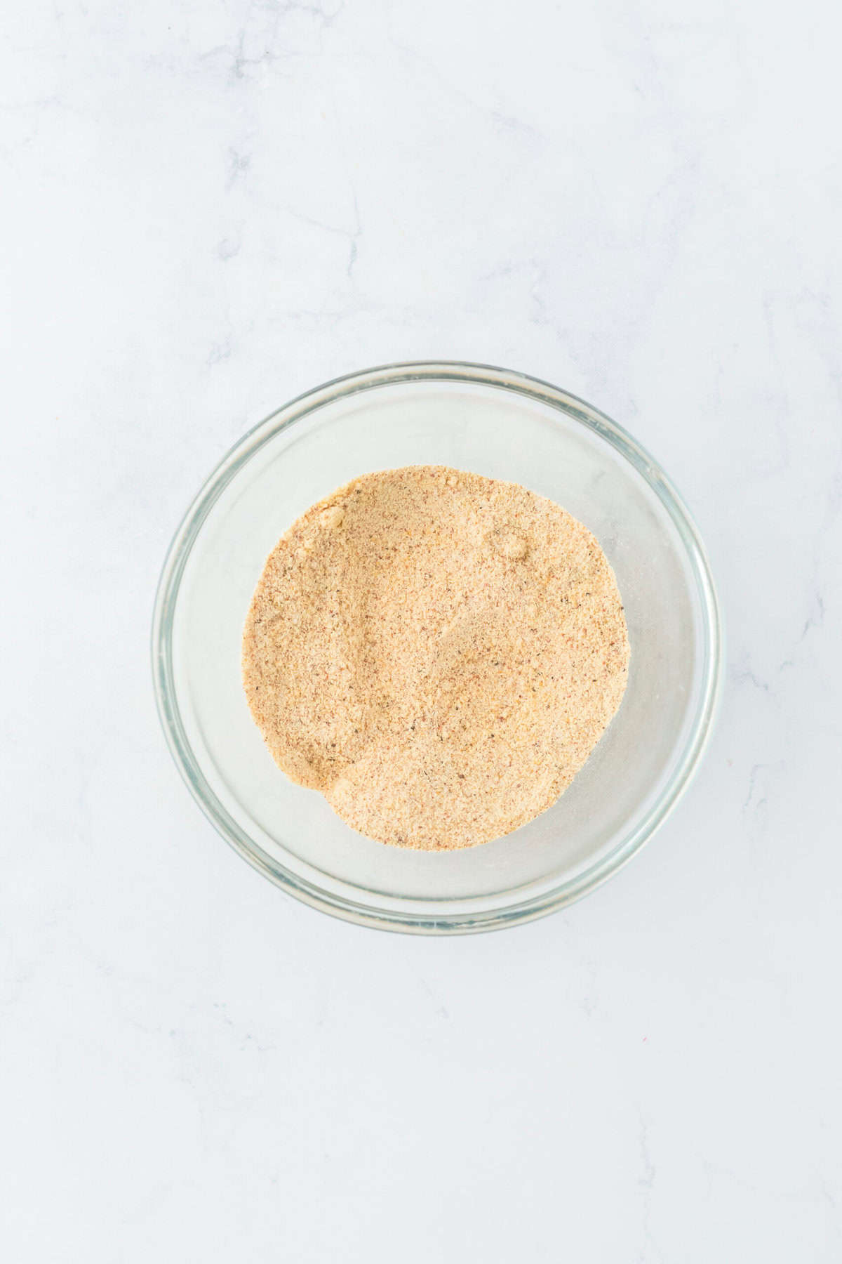 Mixed spices in a glass bowl on white countertop