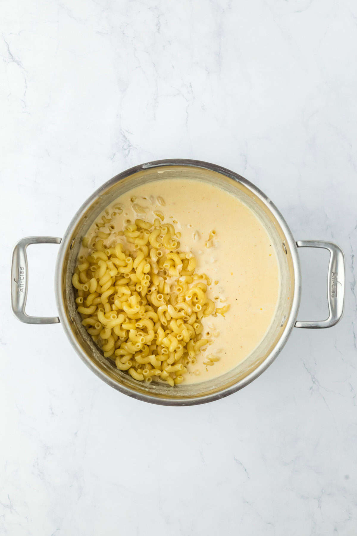 Pasta being added to a cheese sauce in a pot