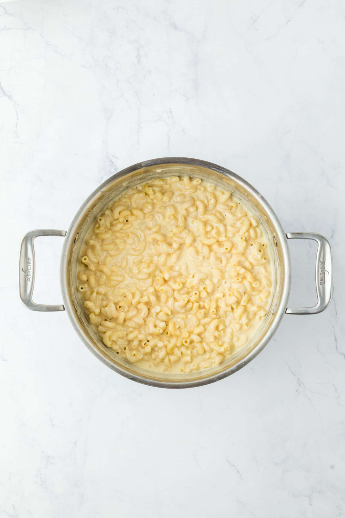 Macaroni being tossed with cheese sauce