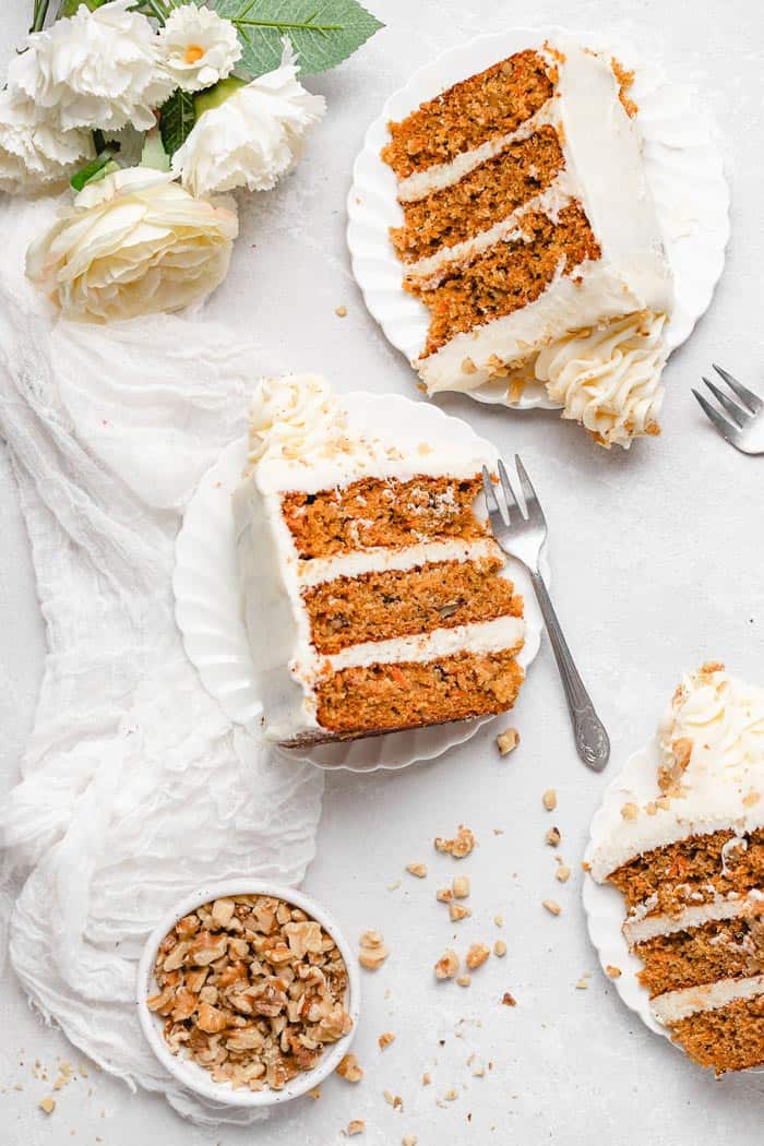 Slices of carrot cake on white plates with silver forks and