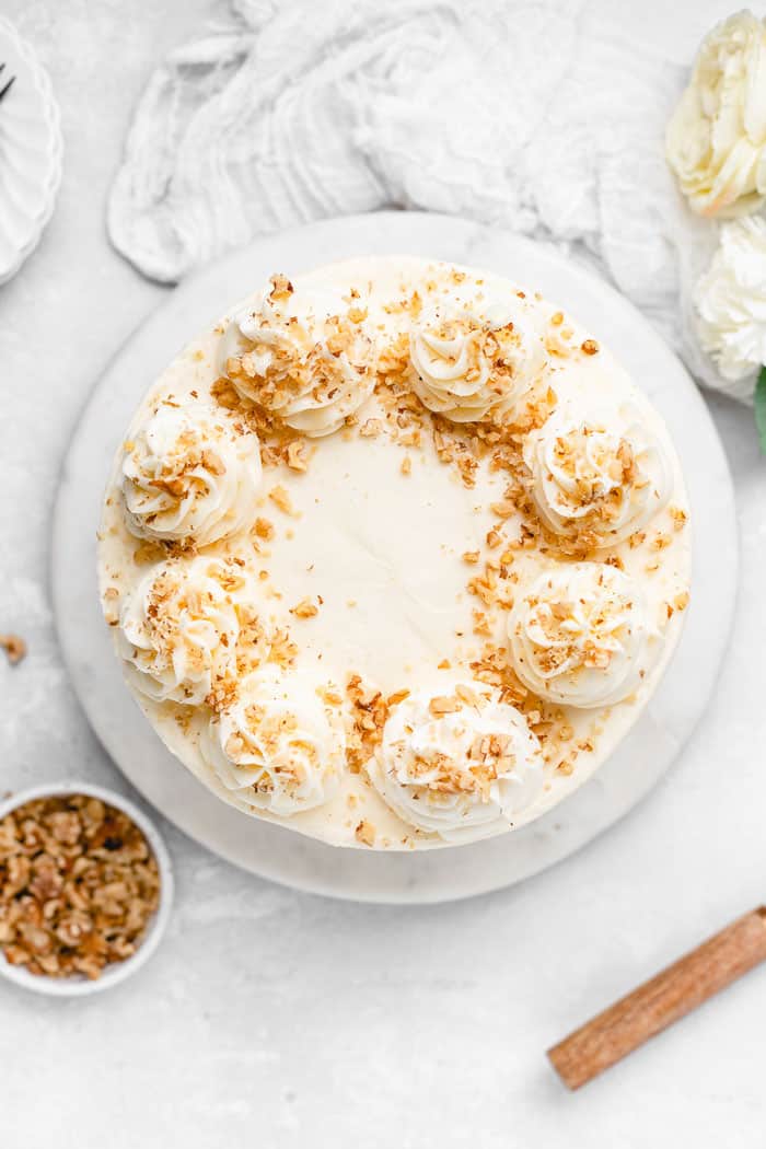 An overhead of full cream cheese frosted carrot cake against white background