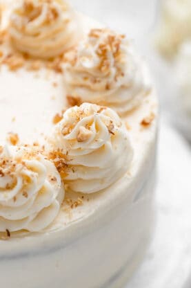 A close up of carrot cake decorated with swirls of buttercream