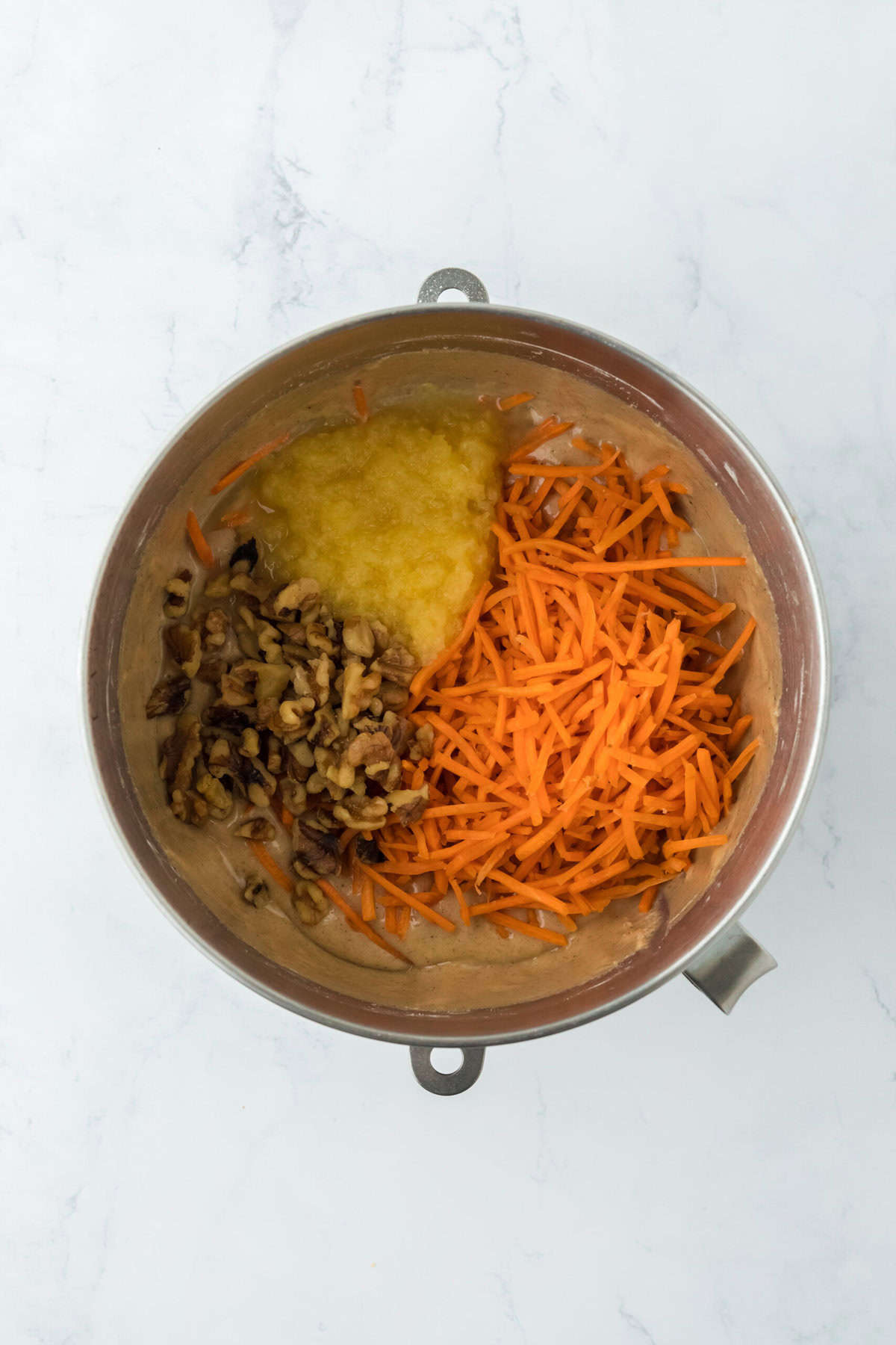 Carrots, pineapple and walnuts being folded into cake batter