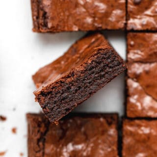 One chewy brownie standing up in the air showing the fudgy inside in a stack of brownies