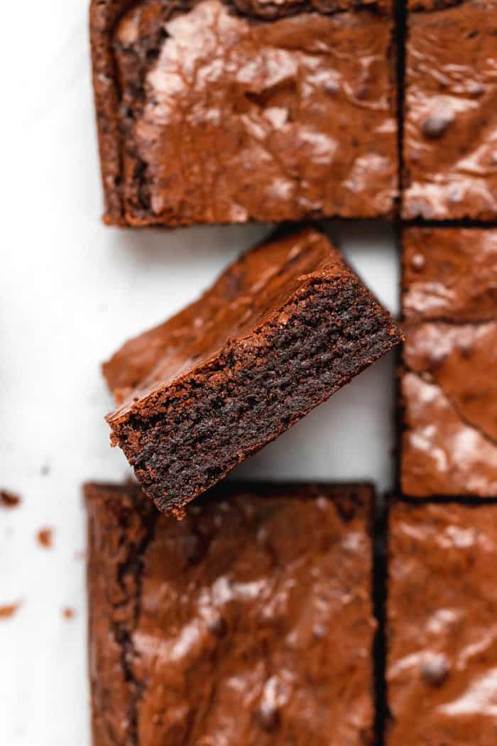 One brownie standing up in the air showing the fudgy inside in a stack of brownies