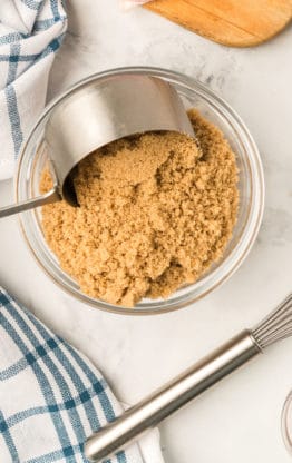 After learning how to make Brown sugar, it is being scooped into a measuring cup for baking