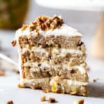 A lovely slice of a hummingbird cake recipe with pineapple cream cheese frosting and nuts ready to eat