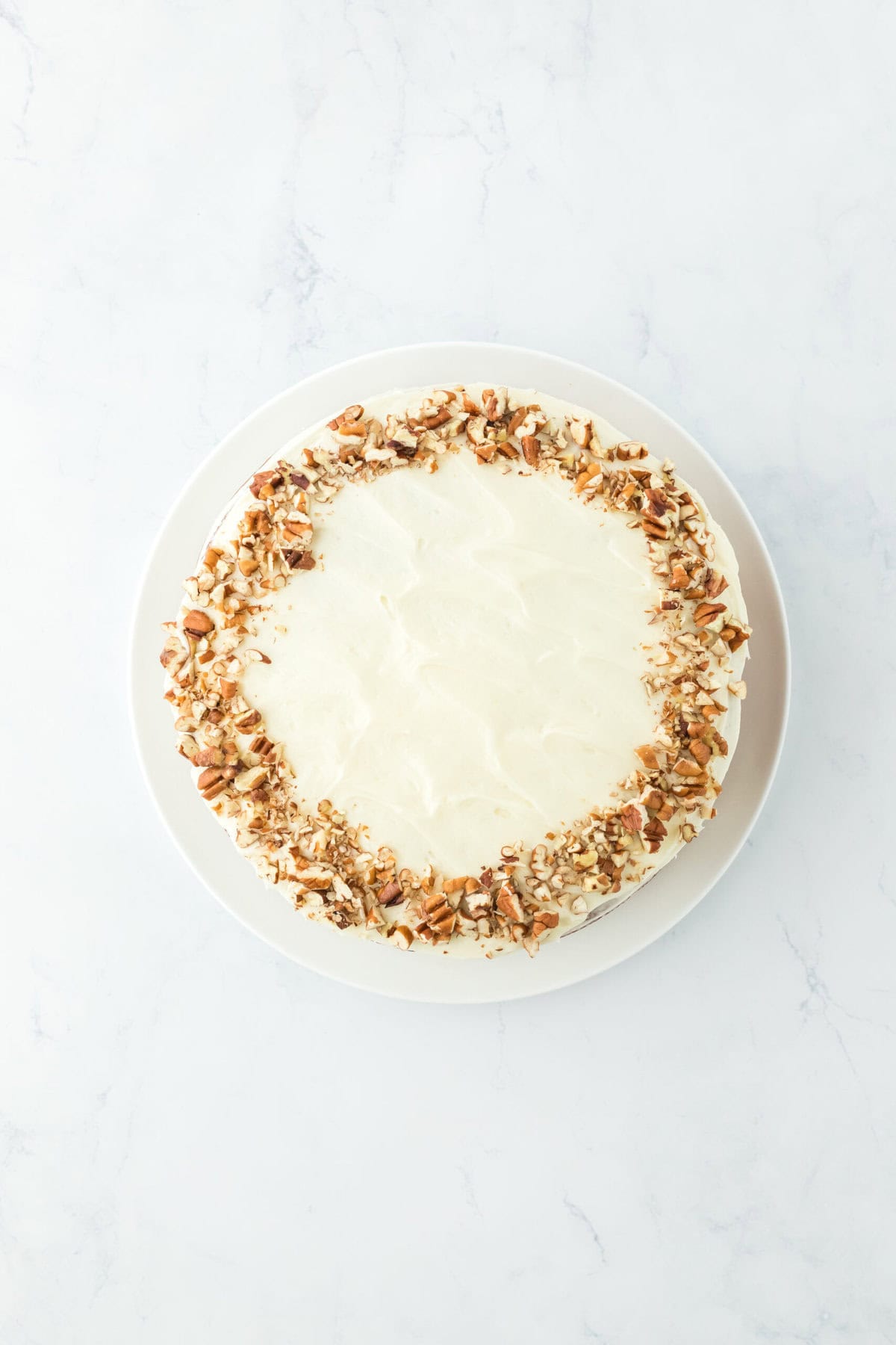 Frosting added to final cake with additional pecans added to the top