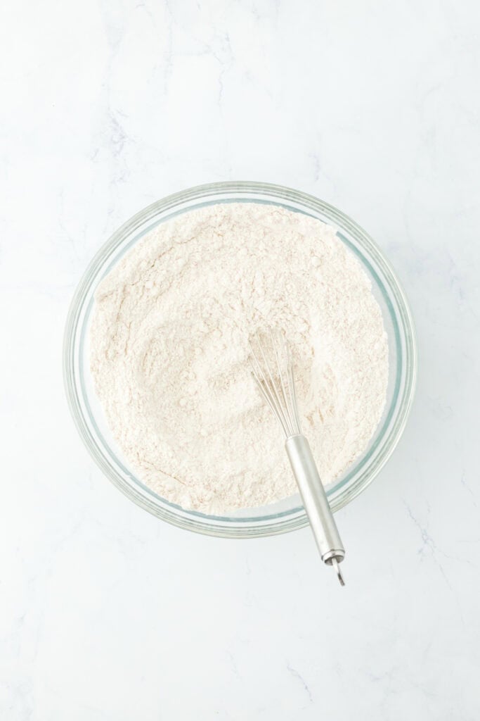 Dry ingredients for a cake in a glass bowl on white countertop