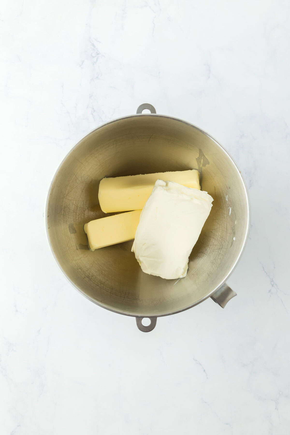 Butter and cream cheese in mixer on white countertop