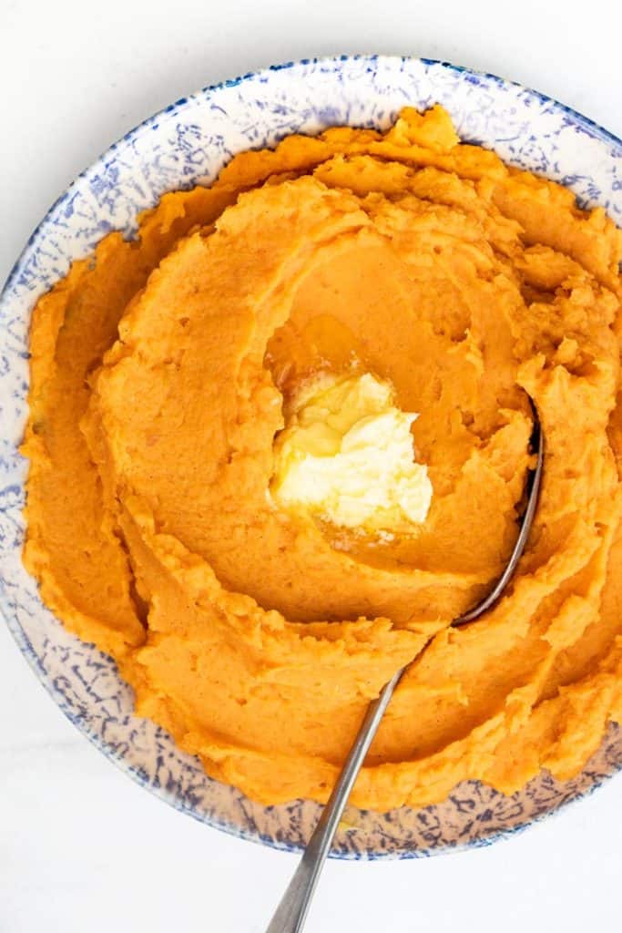 Sweet potatoes mash being mashed with a hand masher