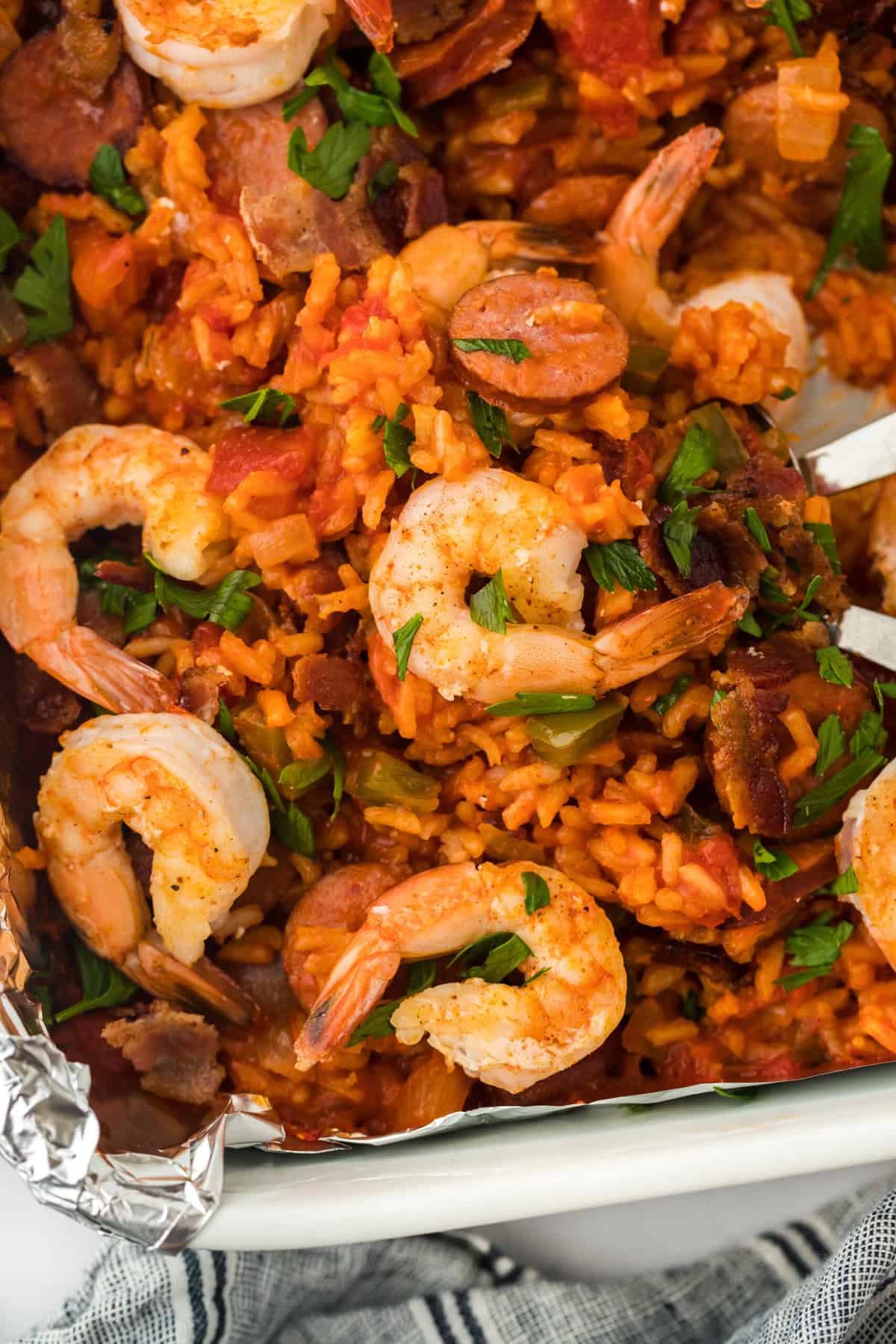 A close up overhead of a red rice recipe with shrimp on top on a white background being dug into with forks