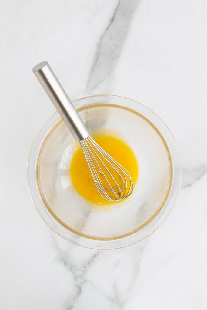 Egg yolks in a separate bowl with a whisk.