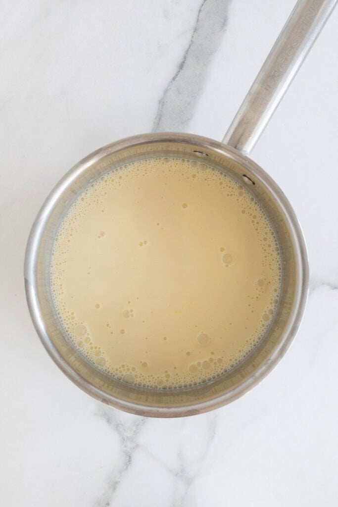 Tempered egg yolks added to a cream mixture in a pot
