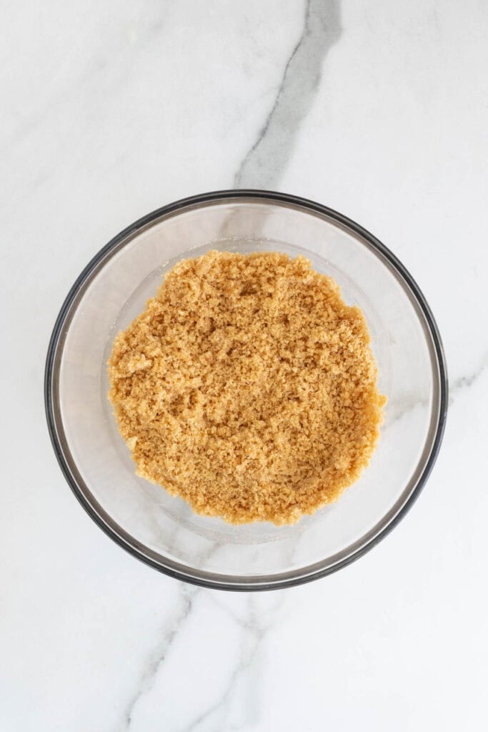 Stirred together cheesecake crust in a glass bowl